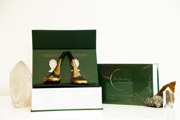 Two gold-tone Victorious Cryo Sticks in an open green presentation box, with a matching carton and decorative crystals.