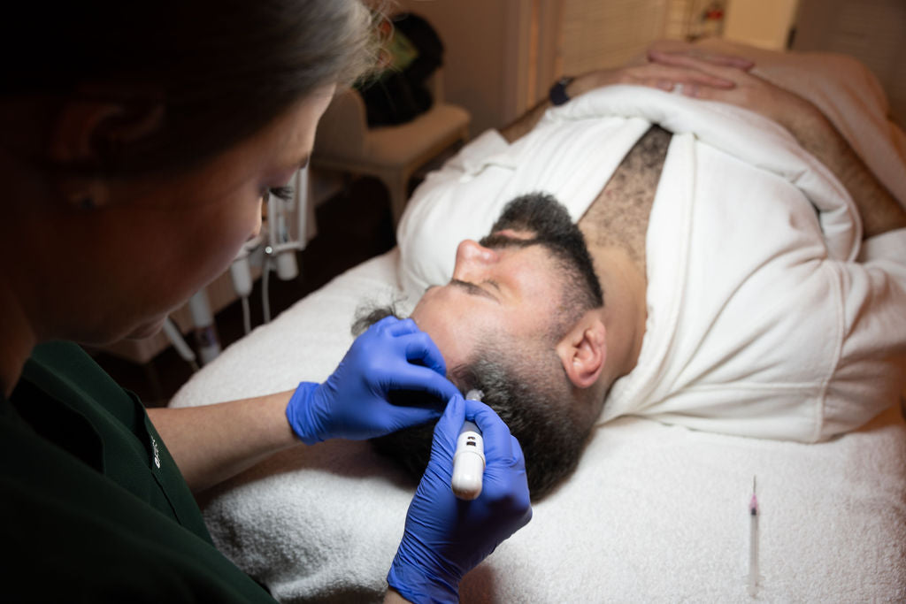 Gloved practitioner uses a pen-shaped treatment device on a person’s scalp, with the person’s face visible.